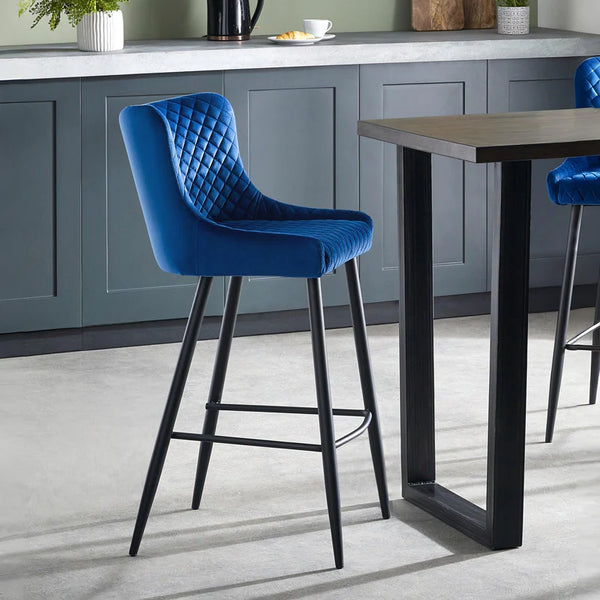 Blue bar stool in a kitchen setting with a table and cabinets.