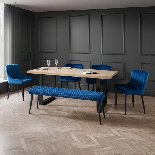 Modern dining room with wooden table, blue chairs, and a bench against a gray paneled wall.