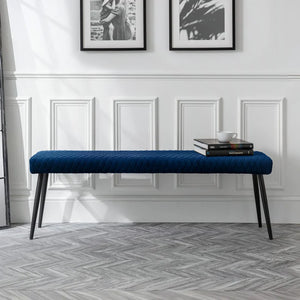 Blue bench in a room with white walls and framed pictures.