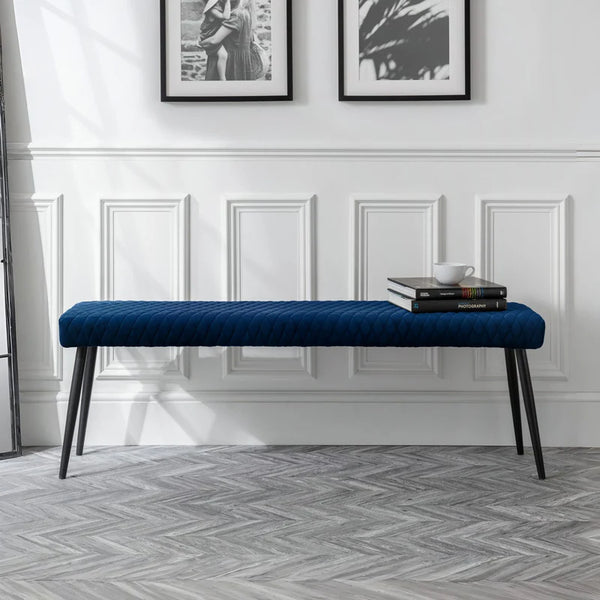 Blue bench in a room with white walls and framed pictures.