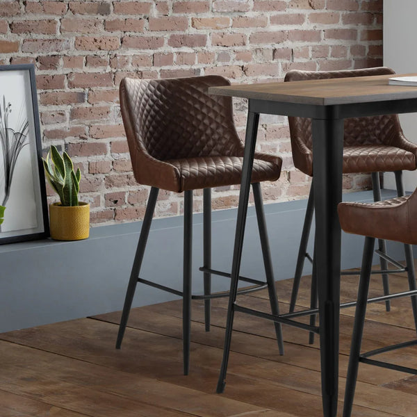 High tables with brown chairs against a brick wall in a modern interior setting.