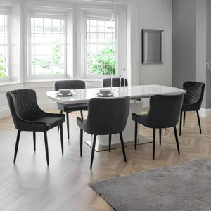 Dining room with a round table and six chairs in a well-lit room.