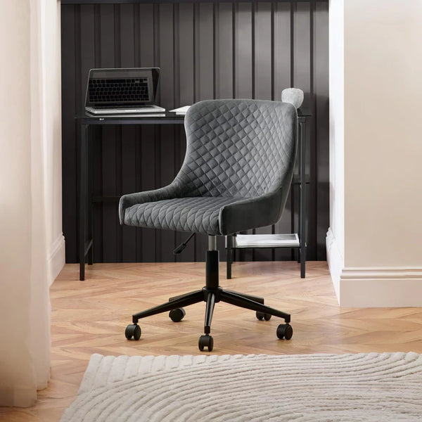 Gray quilted office chair in a room with a desk and computer.