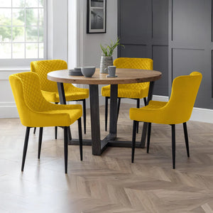 Dining room with a round wooden table and yellow chairs.
