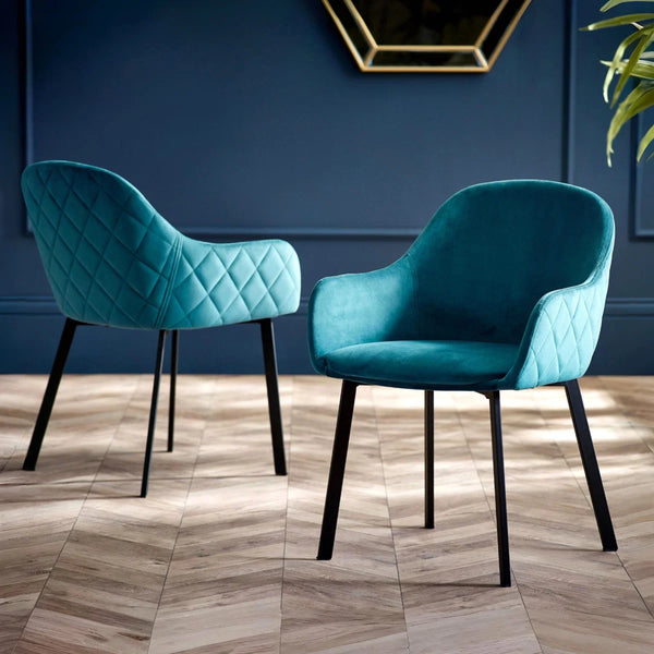 two teal laval dining chairs in a room against a blue wall  