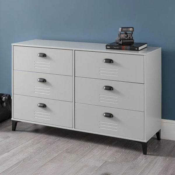 Gray dresser with multiple drawers against a blue wall