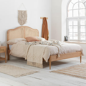 Wooden bed with beige bedding in a bright bedroom with large window