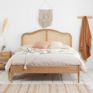 Wooden bed with white bedding and a decorative pillow in a bedroom setting.