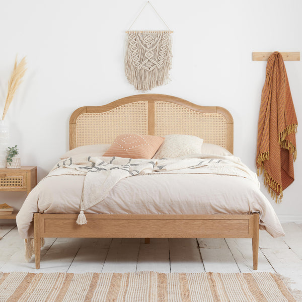 Wooden bed with white bedding and a decorative pillow in a bedroom setting.