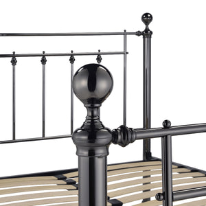 Close-up of a black metal bed frame with decorative posts on a white background