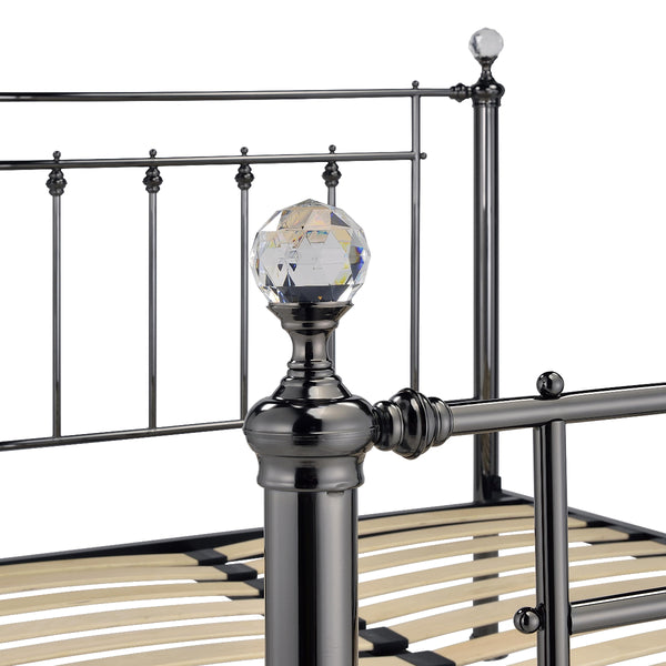Metal bed frame with decorative posts and a crystal ball on a white background