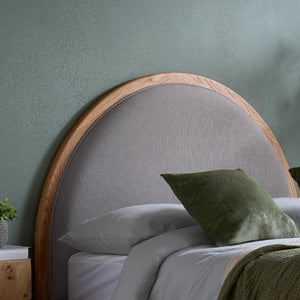 Gray upholstered headboard with wooden frame against a green wall