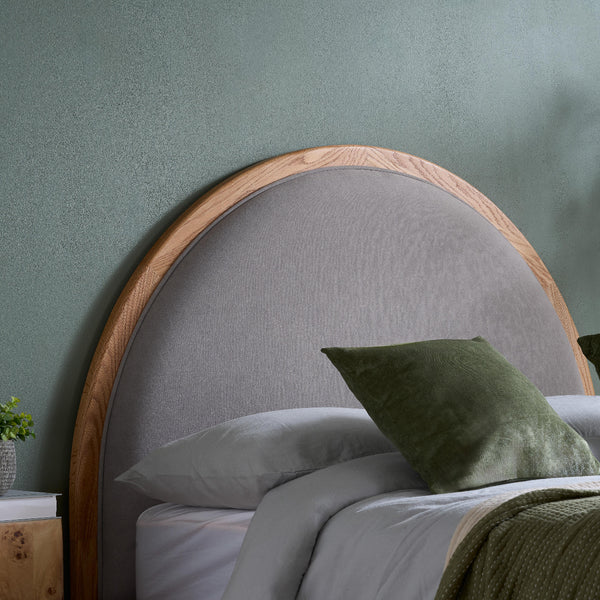 Gray upholstered headboard with wooden frame against a green wall
