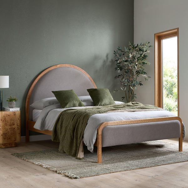 Bedroom with a bed featuring a wooden headboard and green bedding, next to a window and plant.