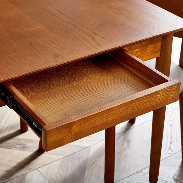 Wooden desk with an open drawer on a wooden floor
