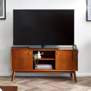 Wooden TV stand with a large flat-screen TV on top in a room with a white wall and wooden floor.