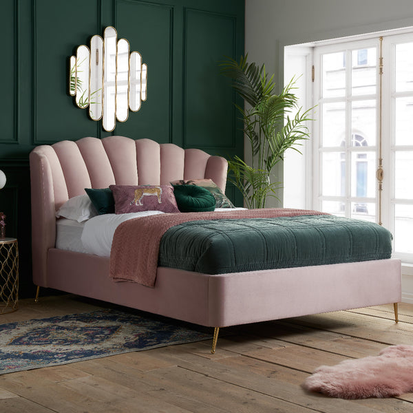 Pink upholstered bed with green bedding in a stylish bedroom.