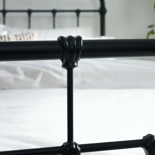 Black metal bed frame with decorative claw-hold feet against a white background
