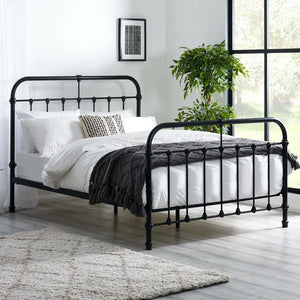 Black metal bed frame with white bedding in a room with a large window and plant.