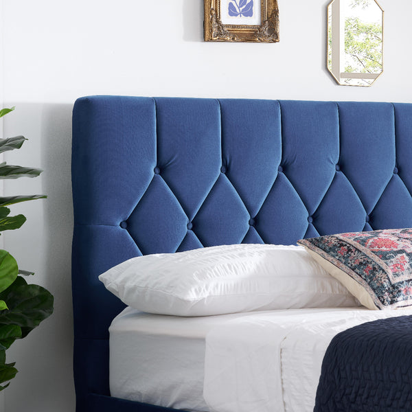 Blue tufted headboard with white bedding and decorative pillows in a bedroom setting.