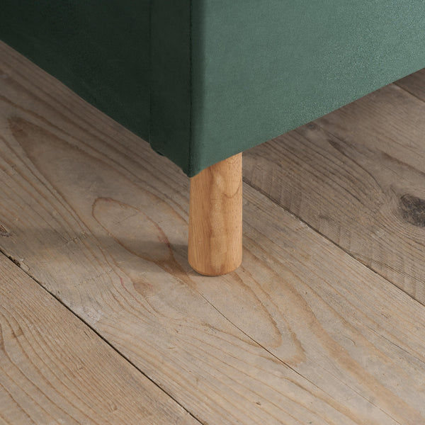 Green upholstered chair leg on a wooden floor