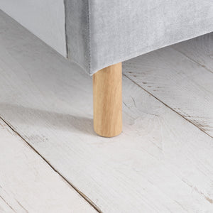 Close-up of a wooden leg of a piece of furniture on a light wooden floor.