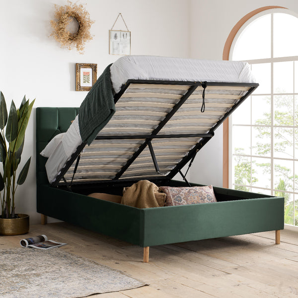 Green bed with storage compartment open in a bright room with plants and decor.