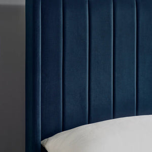 Navy blue upholstered headboard with a pillow on a gray background