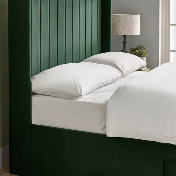 Bed with white bedding and green headboard in a room setting