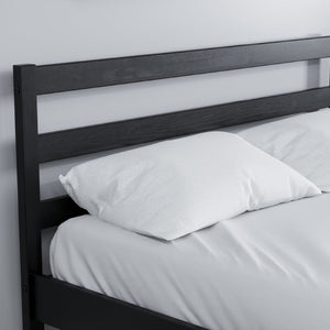 Black wooden headboard with white bedding on a plain background