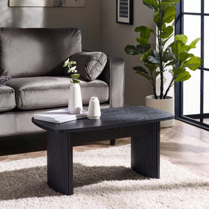 Modern living room with a gray sofa, black coffee table, and decorative plants.