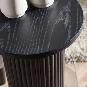 Round black table with textured surface and cylindrical base