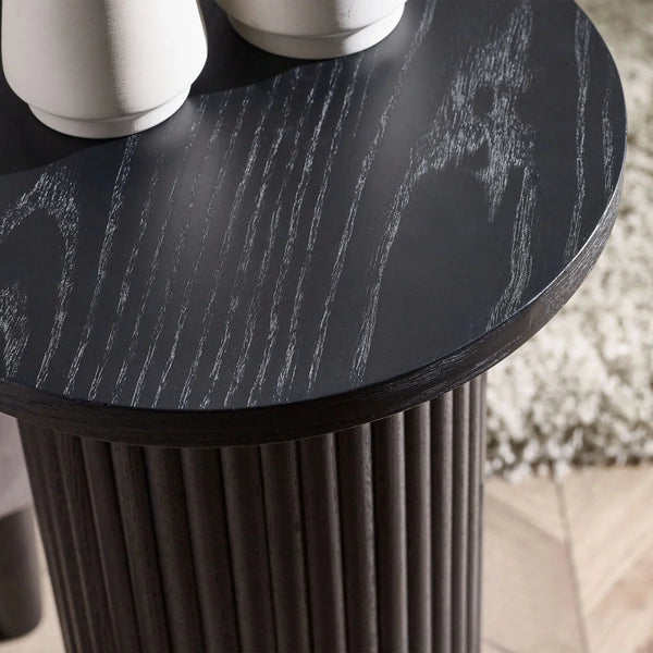 Round black table with textured surface and cylindrical base