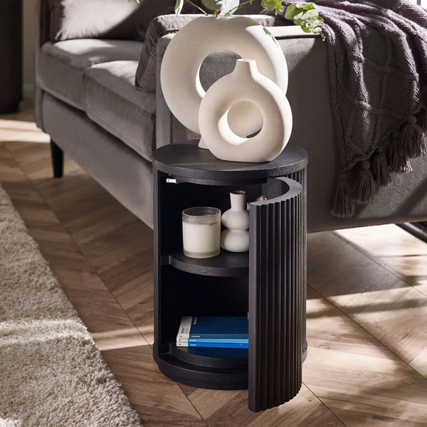 Black side table with decorative items in a living room setting