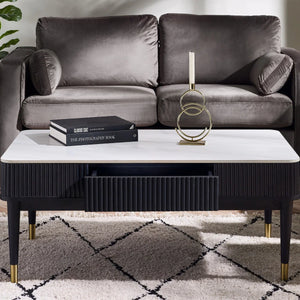 Gray sofa with a coffee table featuring a book and decorative object, on a patterned rug.