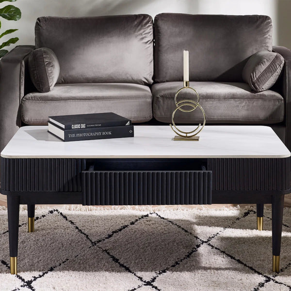Gray sofa with a coffee table featuring a book and decorative object, on a patterned rug.