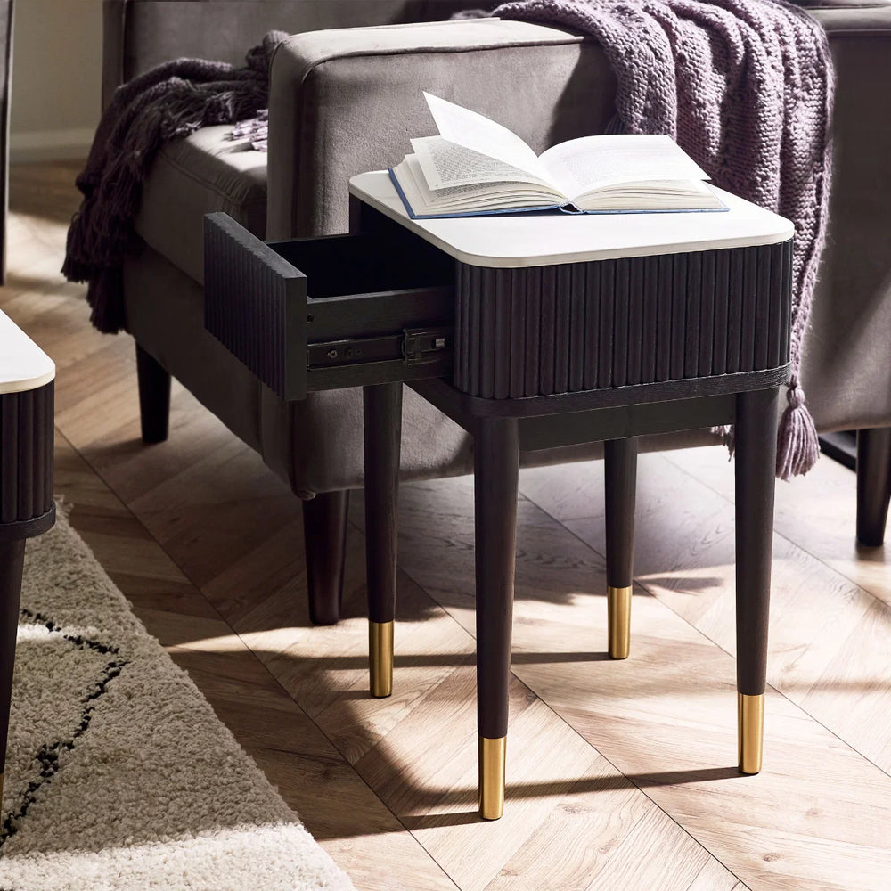 Black side table with white top and gold legs on a white background