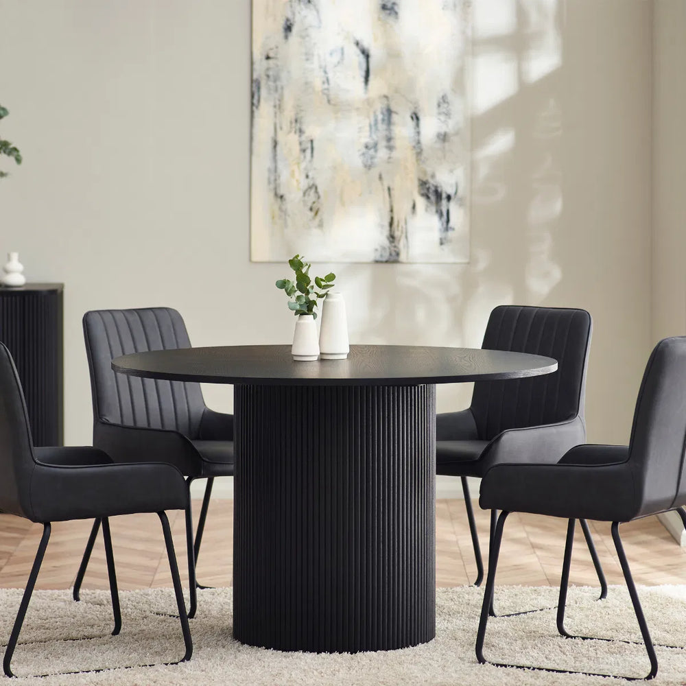Round black table with ribbed cylindrical base on a white background