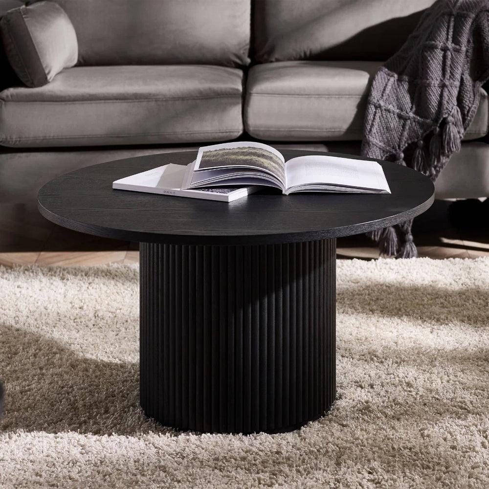 Round black table with ribbed cylindrical base on a white background