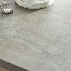 Close-up of a gray concrete countertop with a glass and plates on it.