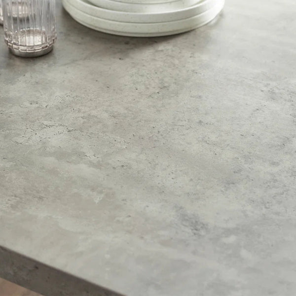 Close-up of a gray concrete countertop with a glass and plates on it.