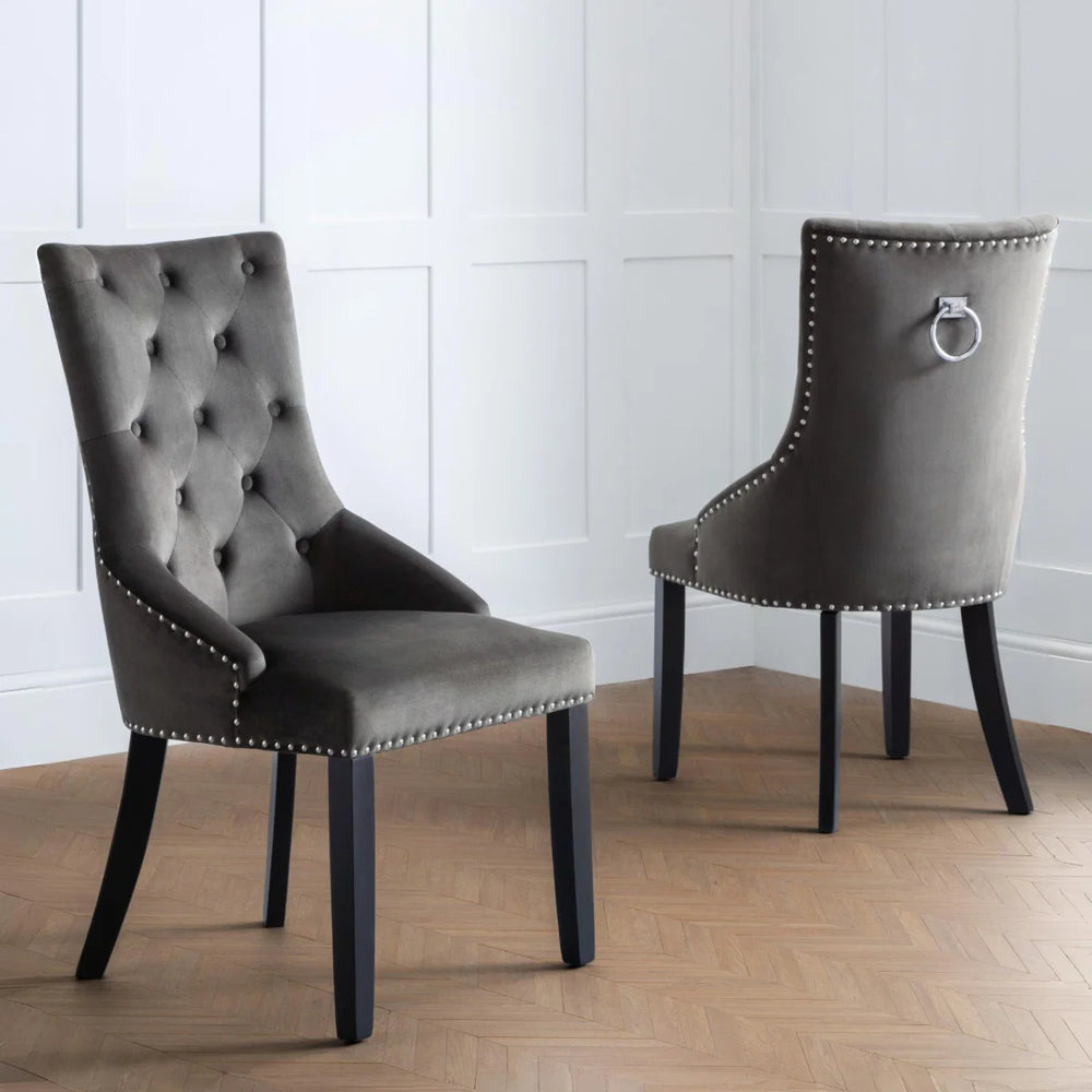 Two gray upholstered chairs with button tufting on a white background