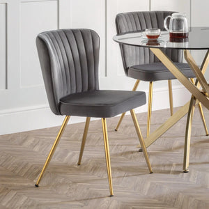MONZA DINING CHAIR CLOSE UP AROUND A GLASS DINING TABLE WITH GOLD METAL LEGS IN A DINING ROOM SETTING