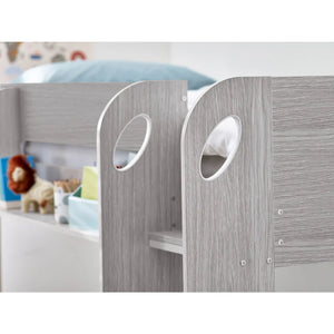 Children's bed with gray wooden panels and white bedding, surrounded by toys.