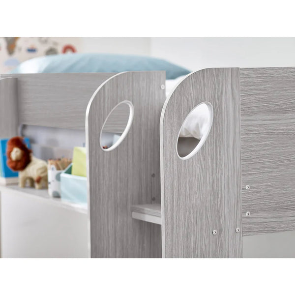 Children's bed with gray wooden panels and white bedding, surrounded by toys.