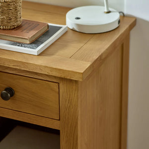 Wooden desk with a drawer, books, and a lamp on top.