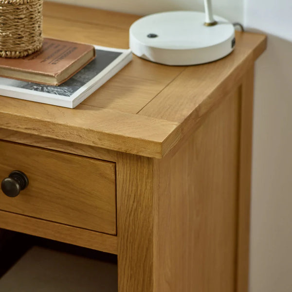 Wooden desk with a drawer, books, and a lamp on top.