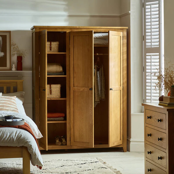 Wooden wardrobe in a bedroom with bed and dresser visible