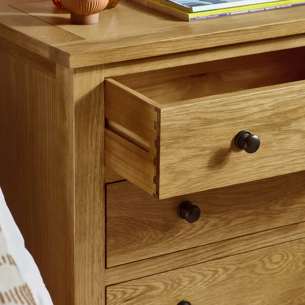Wooden dresser with open drawer and black knobs