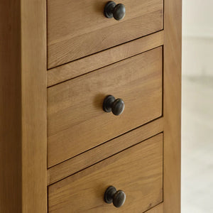 Wooden dresser with three drawers and metal knobs on a neutral background